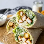 Delicious Chicken Caesar Wrap sliced in half, revealing romaine lettuce, grilled chicken, and Parmesan cheese inside.