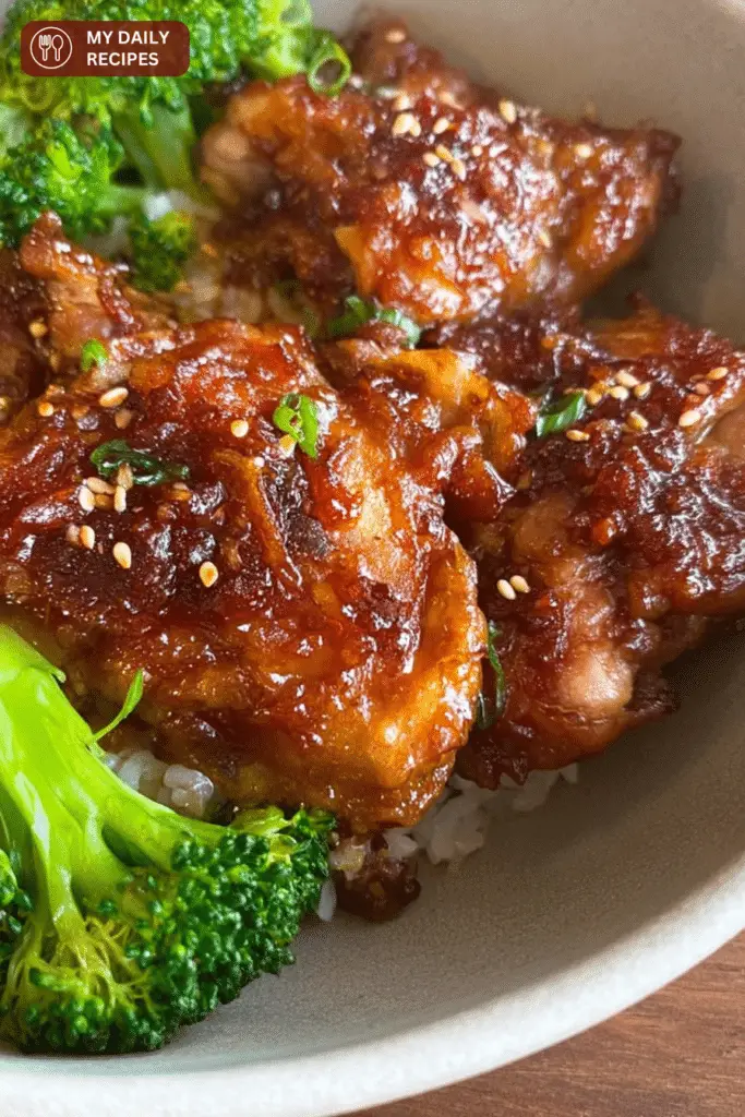 Plated easy soy garlic chicken thighs garnished with sesame seeds and green onions, served with rice and vegetables.