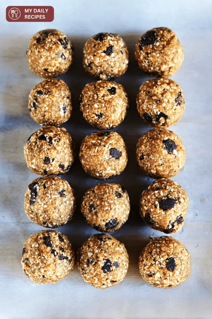 Close-up of healthy no-bake protein balls on a plate, surrounded by oats and chocolate chips, perfect for a nutritious snack or breakfast.
