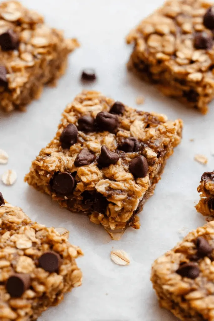 Close-up of sliced banana peanut butter oatmeal bars on a cutting board with peanut butter drizzle and chocolate chips
