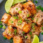 Plated Bang Bang Salmon with sauce, lime wedges, and fresh herbs