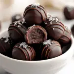 Close-up of brownie truffles covered in chocolate and colorful sprinkles on a white plate