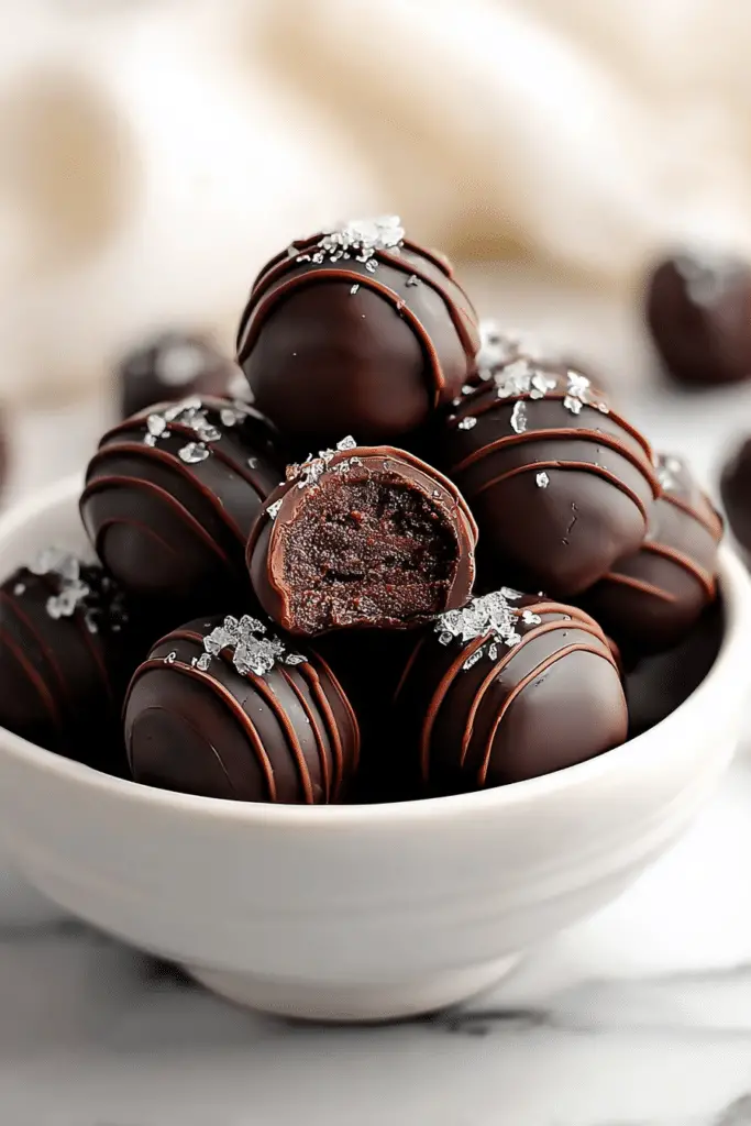 Close-up of brownie truffles covered in chocolate and colorful sprinkles on a white plate