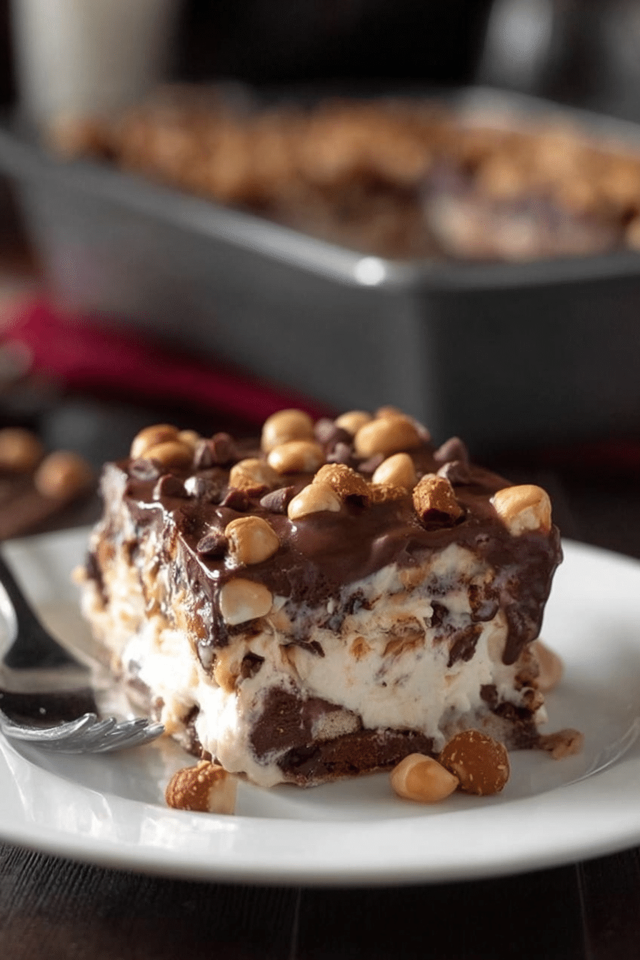 Close-up of a sliced Buster Bar Ice Cream Cake revealing layers of ice cream, fudge, and red skin peanuts.