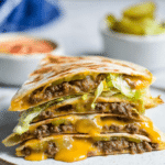 Delicious cheeseburger quesadillas filled with melted cheddar cheese and ground beef, served with pickle chips.