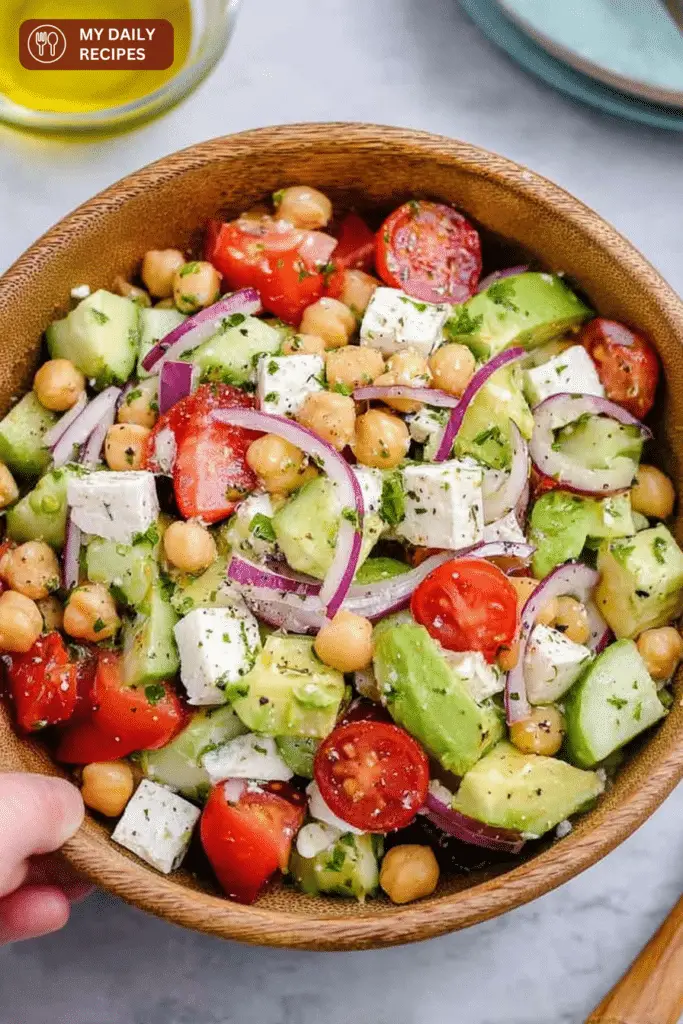 Close-up of a Chickpea Feta and Avocado Salad with cherry tomatoes, cucumbers, and feta cheese in a bowl.