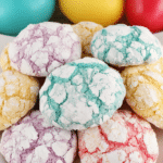 Close-up of colorful lemon crinkle cookies on a plate, dusted with powdered sugar.