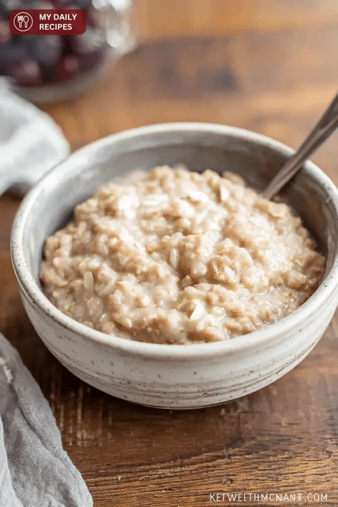 Bowl of creamy oatmeal topped with fresh fruits, nuts, and honey on a rustic wooden table.
