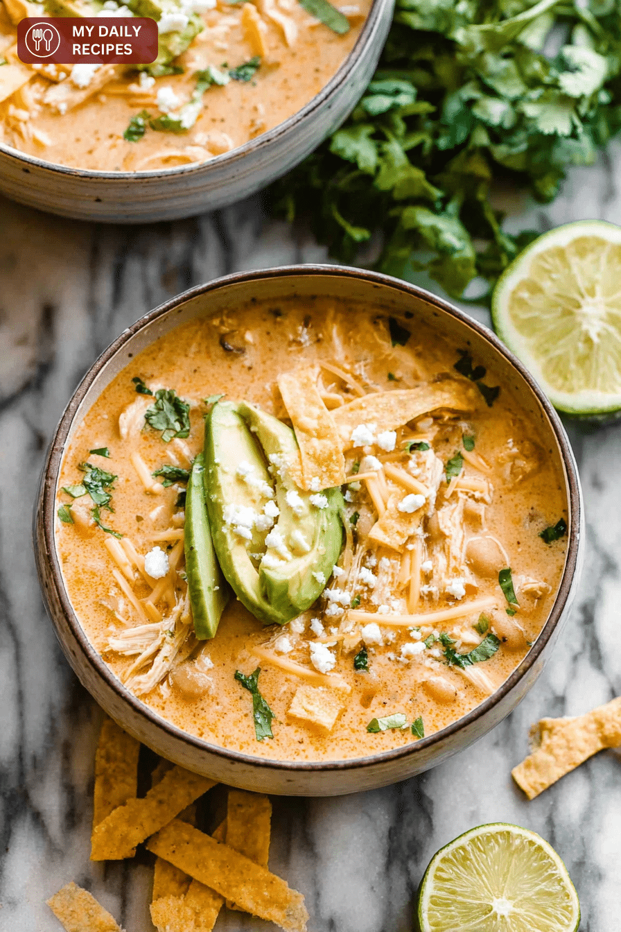 Bowl of creamy white chicken chili with cilantro and avocado, served with tortilla chips.