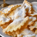 A festive platter of crispy fried Italian crostoli cookies dusted with powdered sugar.