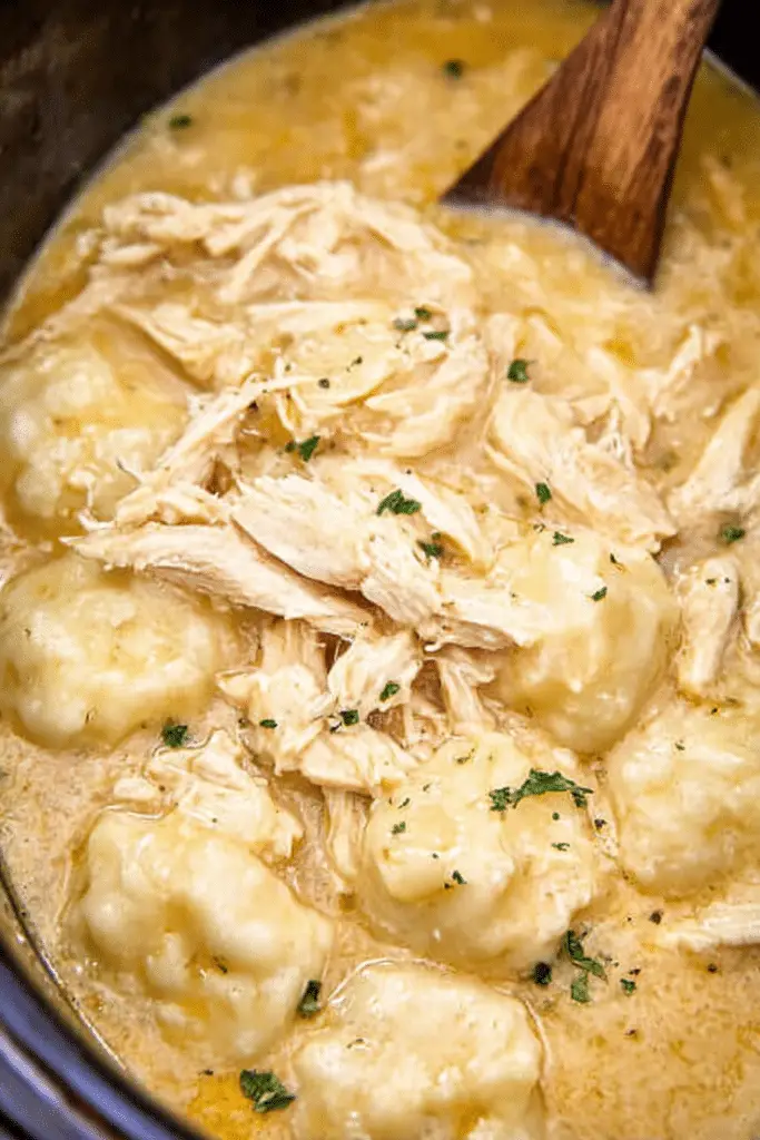 Bowl of crock pot chicken and dumplings garnished with parsley and cracked pepper