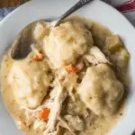 Delicious bowl of easy chicken and dumplings with biscuits, garnished with herbs