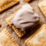 Close-up of homemade frosted brown sugar cinnamon pop tarts with icing and decorative elements like cinnamon sticks and brown sugar.