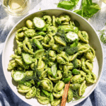 A colorful serving of green goddess pasta salad with fresh herbs, asparagus, and peas in a bowl.
