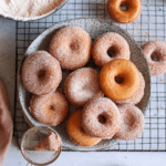Homemade mini donuts coated in cinnamon sugar served on a rustic wooden plate.