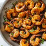 Delicious honey garlic shrimp dish with green onion and cilantro garnish served alongside rice.