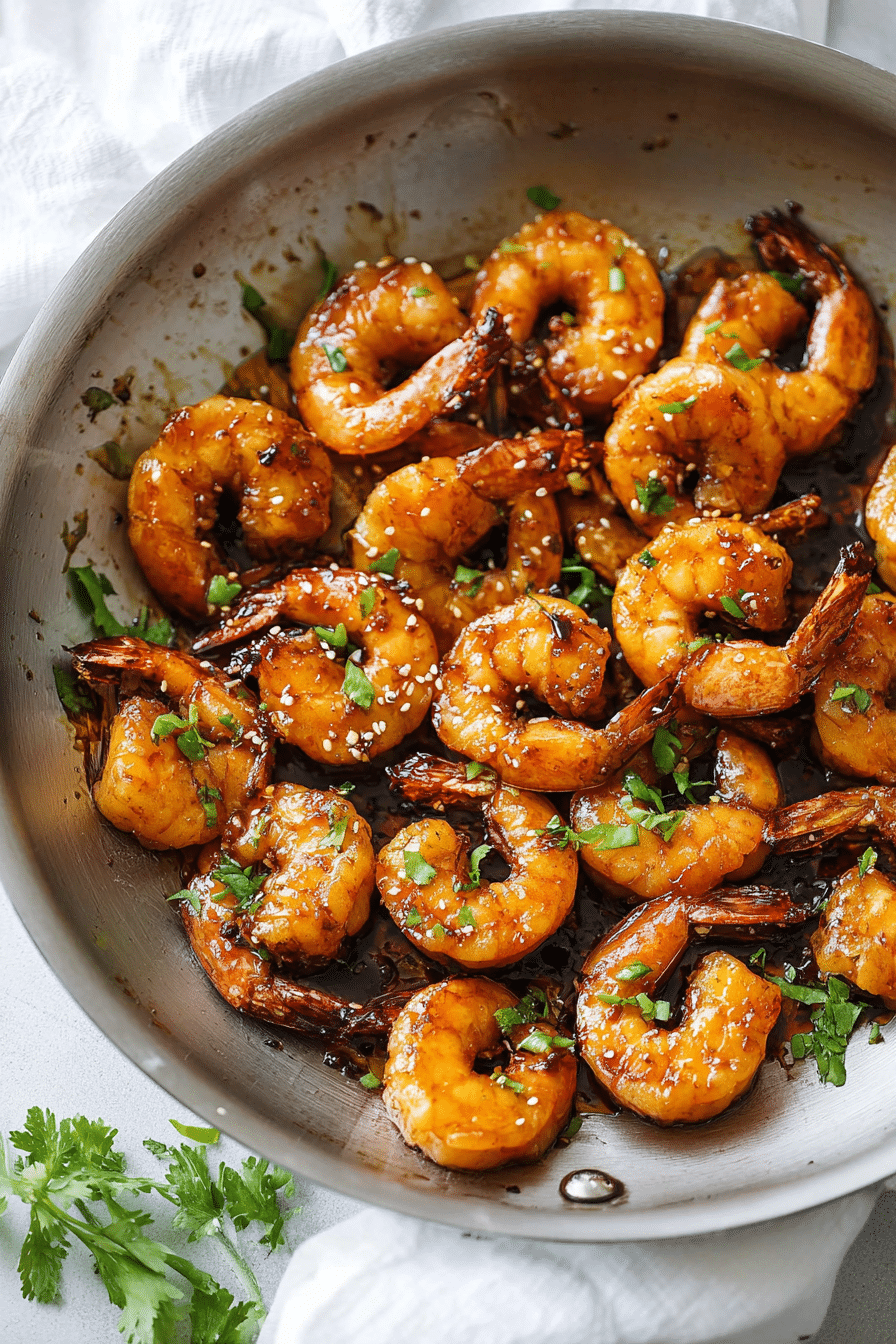 Delicious honey garlic shrimp dish with green onion and cilantro garnish served alongside rice.