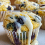 Close-up of lemon blueberry cupcakes with frosting, fresh blueberries, and lemon slices on a pastel plate.