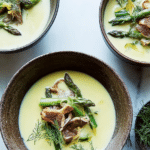 Bowl of lemony roasted asparagus soup garnished with dill and oregano, topped with roasted asparagus and mushrooms.