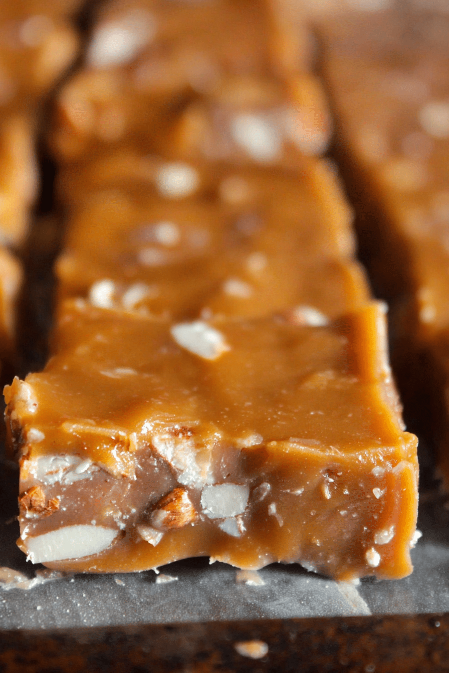 Close-up of cut squares of Oklahoma Nut Candy on a decorative plate with walnuts scattered around.