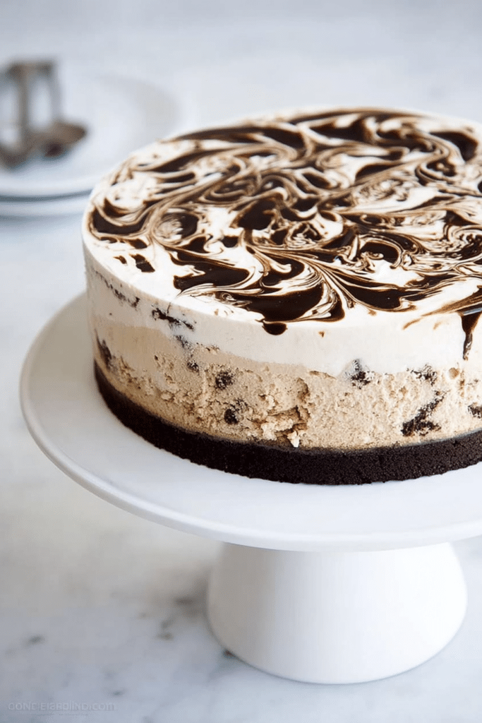 Slice of coffee ice cream cake featuring brownie base, creamy coffee ice cream filling, and a fudge swirl on a rustic wooden table.