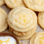 Stack of soft and chewy lemon cookies sprinkled with lemon zest and sugar, highlighting their fluffy texture.