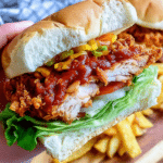 Close-up of a spicy crispy chicken burger with melted cheese and fresh lettuce, highlighting its crispy texture and juicy filling.