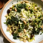 Spring Orzo Salad with asparagus, artichokes, olives, and herbs in a bowl on a wooden table