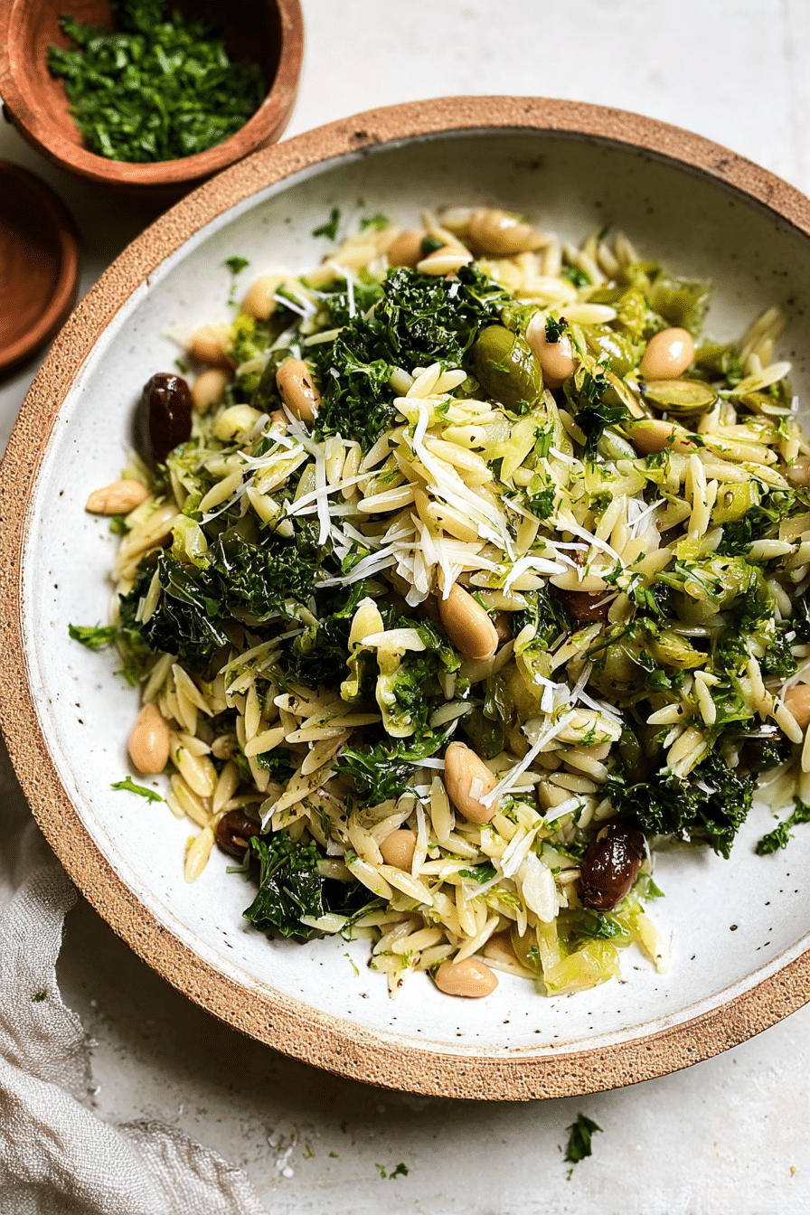 Spring Orzo Salad with asparagus, artichokes, olives, and herbs in a bowl on a wooden table