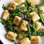 Close-up of spring vegetable brown butter gnocchi with asparagus and peas in a bowl.