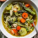 A bowl of spring vegetable soup filled with colorful vegetables and fresh dill, highlighting a healthy meal.