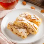 Delicious sweet almond pastry garnished with almonds on a wooden table.