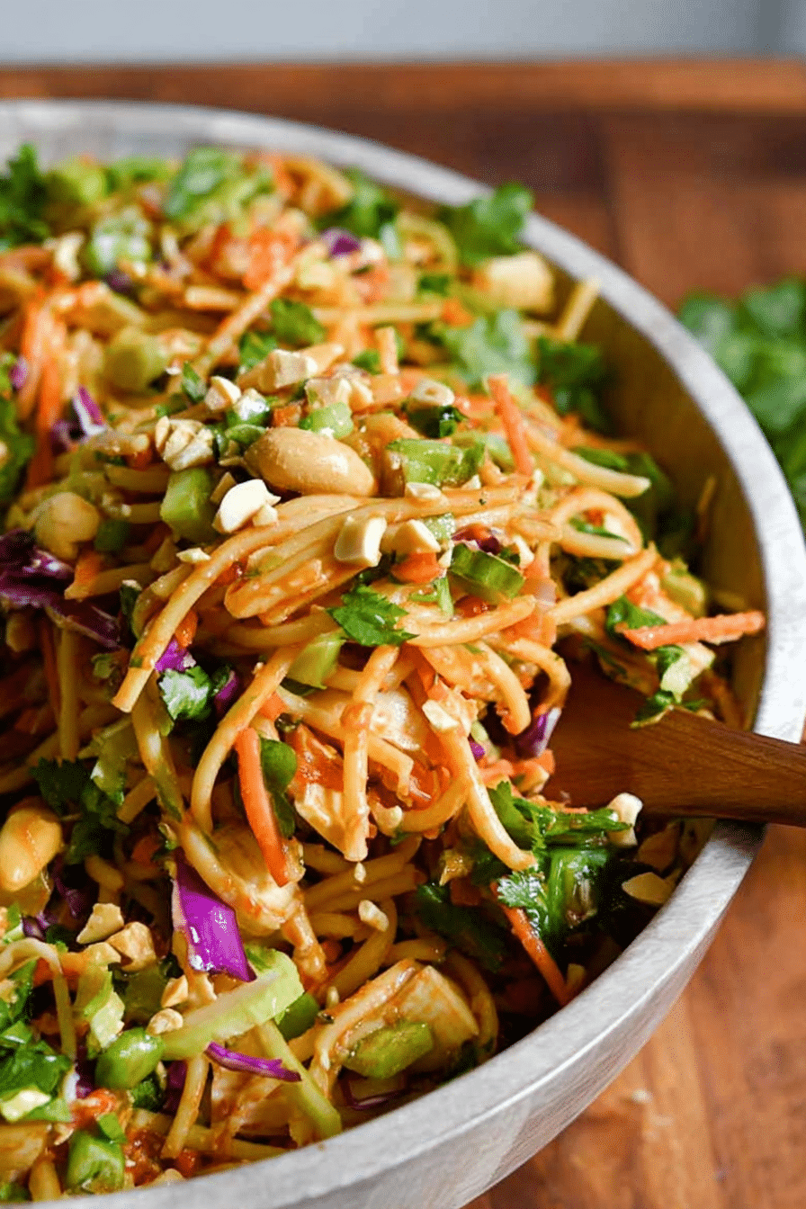 Thai spring roll pasta salad filled with colorful vegetables, shrimp, and topped with peanuts in a bright salad bowl.
