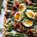 Asparagus egg and prosciutto tart served with arugula salad and lemon slices