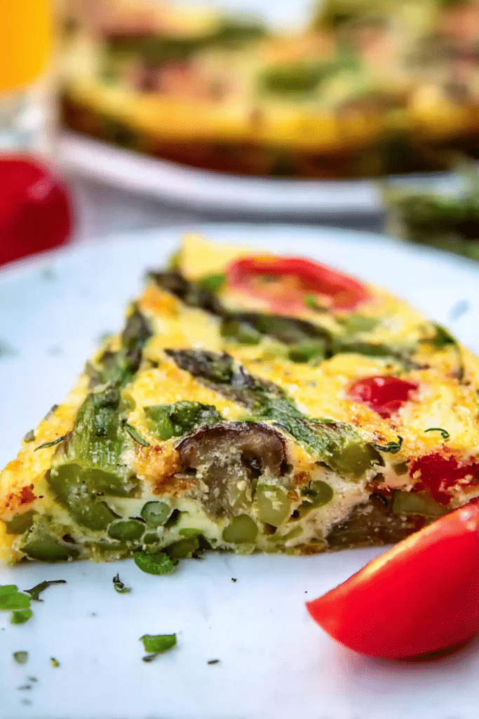 Close-up of a delicious asparagus frittata topped with cherry tomatoes and green onions on a wooden table.