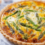 Sliced asparagus quiche with green asparagus and feta cheese on a wooden table