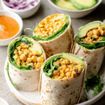 Overhead view of avocado buffalo chickpea salad wraps filled with fresh spinach, diced vegetables, and creamy avocado.