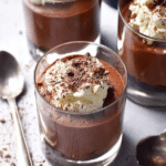 Baileys chocolate mousse topped with whipped cream and chocolate shavings in a glass on a wooden table.