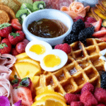 Brunch charcuterie board with waffles, fruits, meats, and baked goods for a delightful breakfast spread.