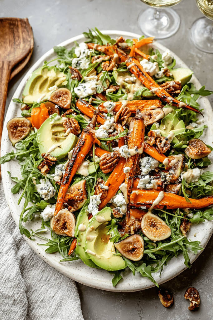 Delicious carrot arugula salad with grilled carrots, avocado, figs, goat cheese, and walnuts drizzled with tahini dressing.
