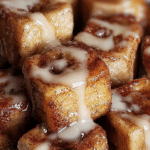 Golden brown cinnamon roll french toast bites served with powdered sugar and strawberries.