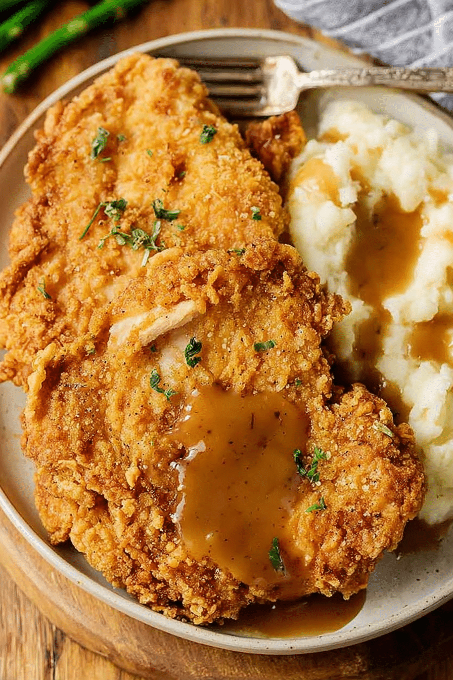 Delicious country fried chicken served with creamy mashed potatoes and rich gravy, perfect for a family dinner.
