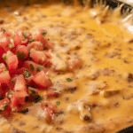 Creamy smoked queso in a cast iron skillet with melted cheese and cilantro, served with tortilla chips.