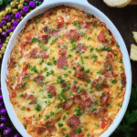 Delicious easy Mardi Gras hot muffuletta dip in a vibrant dish, garnished with parsley and served with bread slices, perfect for appetizers.