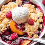 Delicious easy peach and raspberry cobbler with fresh peaches and raspberries on a wooden table.
