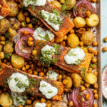 Easy sheet pan salmon dinner with potatoes and chickpeas topped with herby yogurt sauce and fresh herbs