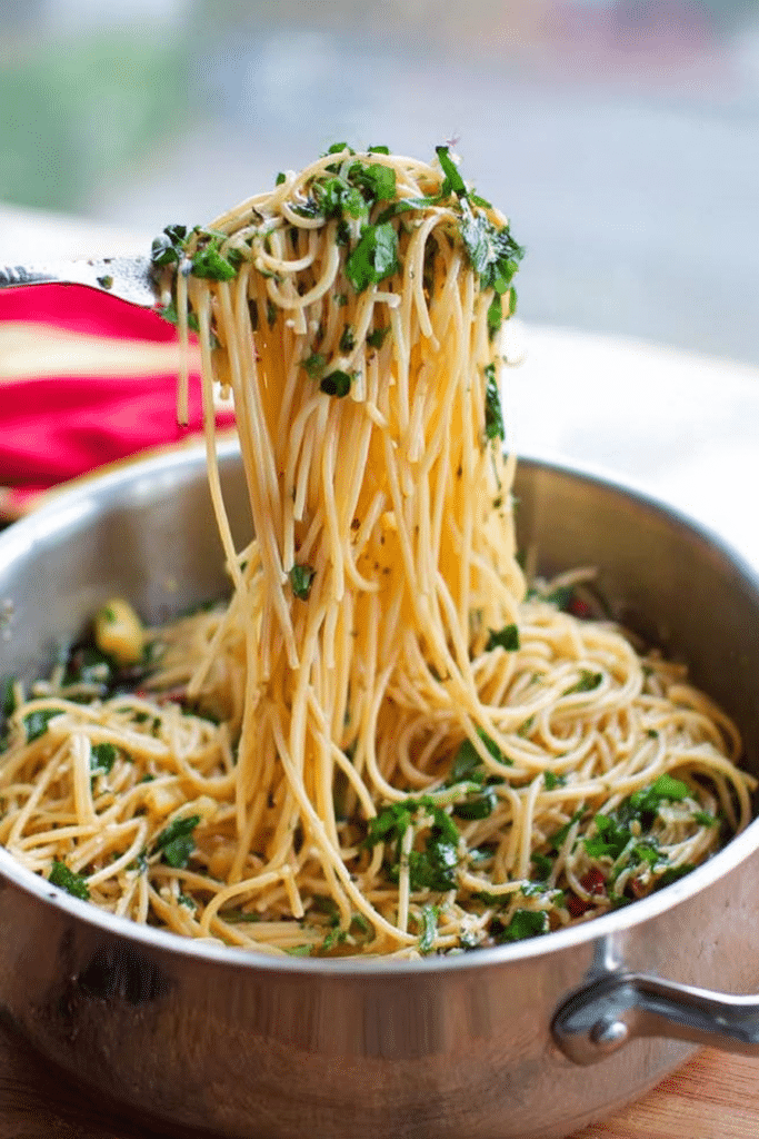 Close-up of garlic butter spaghetti garnished with fresh basil and Parmesan cheese on a rustic wooden table.