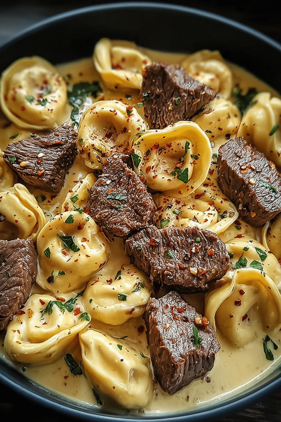 Delicious garlic steak tortellini served in a bowl, featuring creamy parmesan sauce and garnished with fresh parsley.