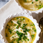 A bowl of Greek lemon chicken soup with feta and chives, showcasing its bright flavors and comforting texture.