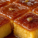 Slice of Greek Ravani semolina cake garnished with powdered sugar and orange zest